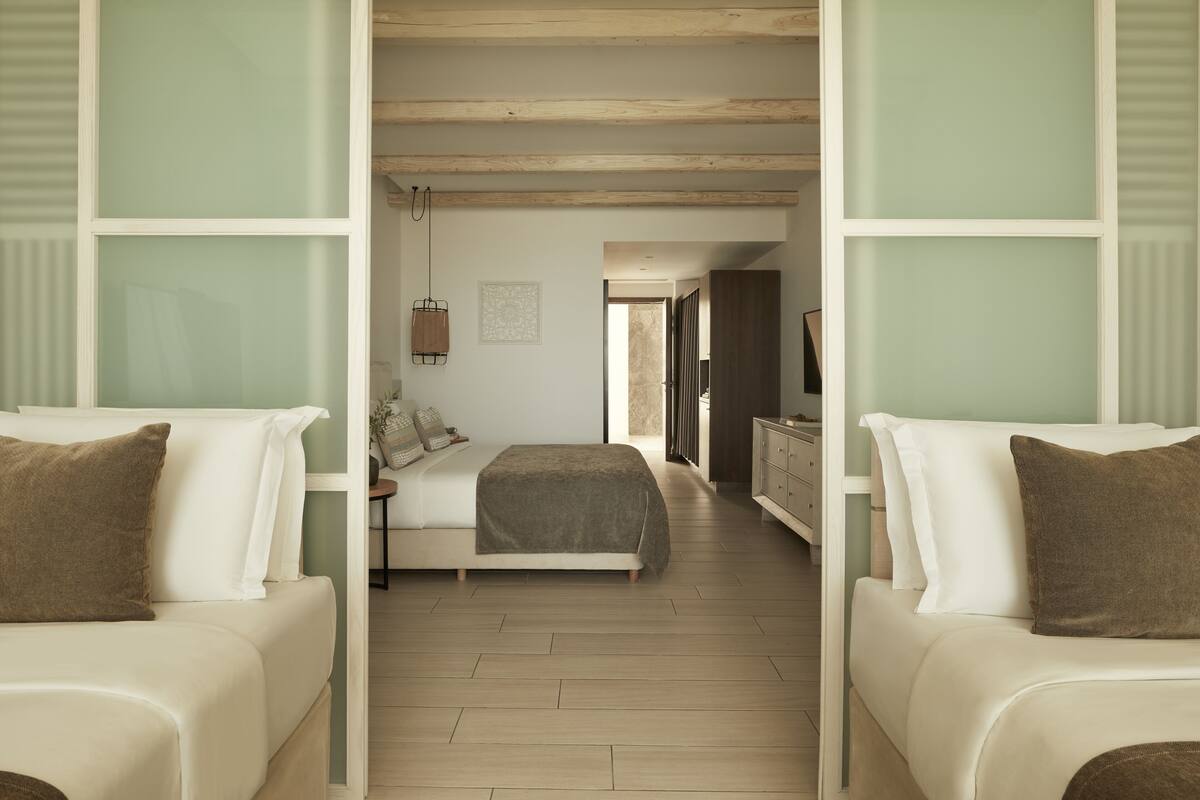 Een hotelkamer met een bed, twee banken, een dressoir en een televisie.