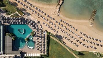 Vista aérea de un resort con piscina, tumbonas y zona de playa.