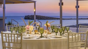 A table set for a meal with a view of the sea and a rocky island.