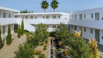 Un edificio moderno con varios pisos, un patio central con fuente de agua y palmeras.