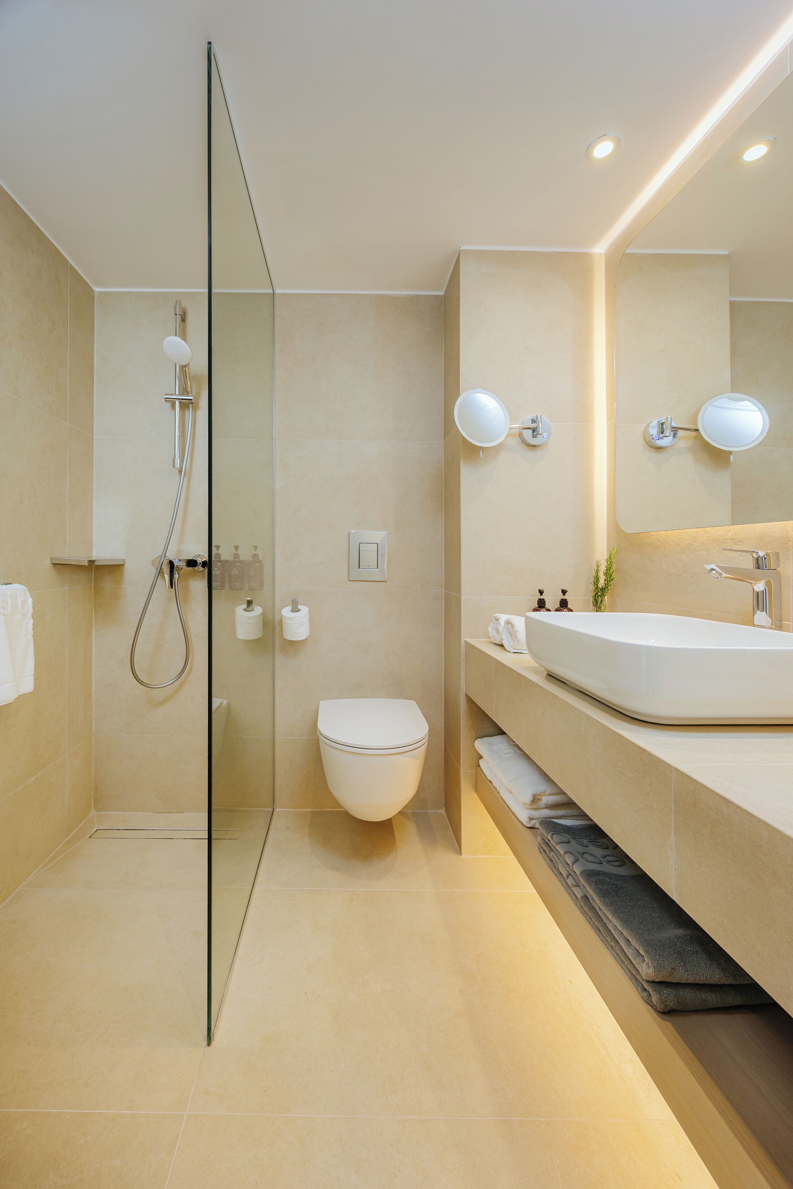 Een moderne badkamer met een glazen douchecabine, toilet en een wastafel met spiegel.