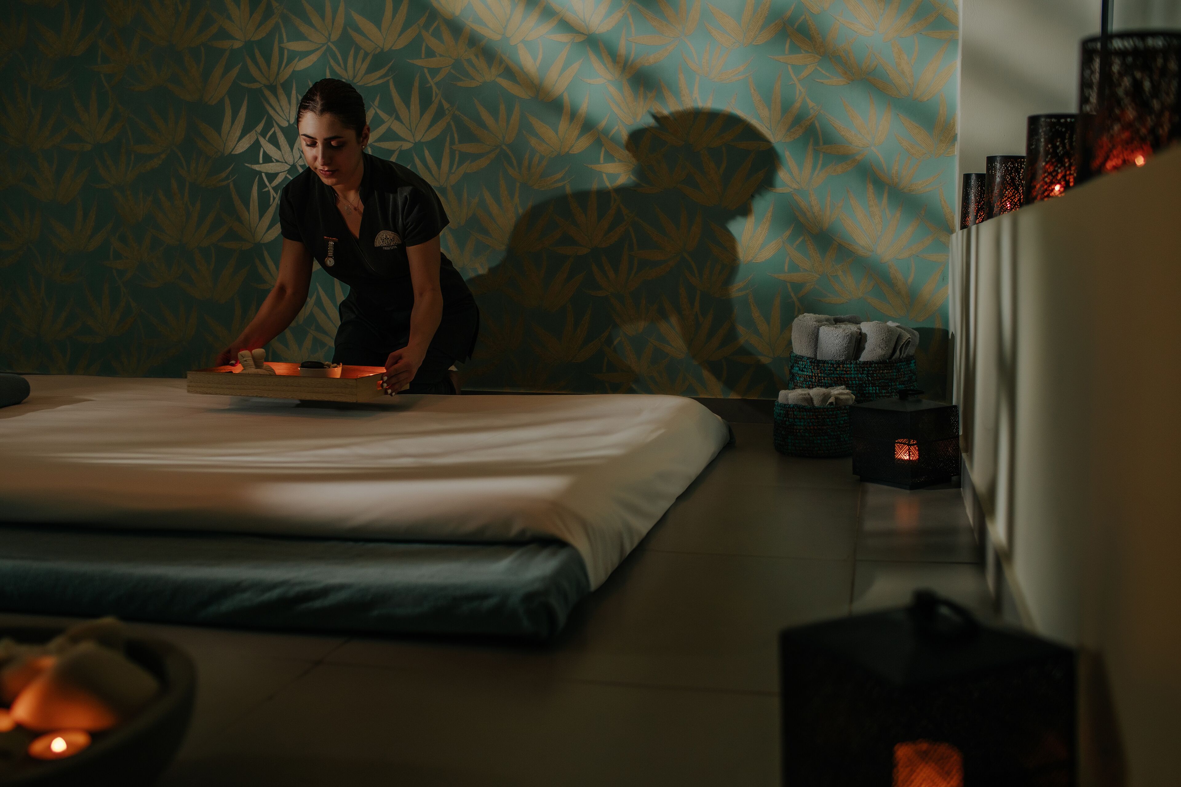 Ett hotellrum med en säng, ett massagebord och en massageterapeut.