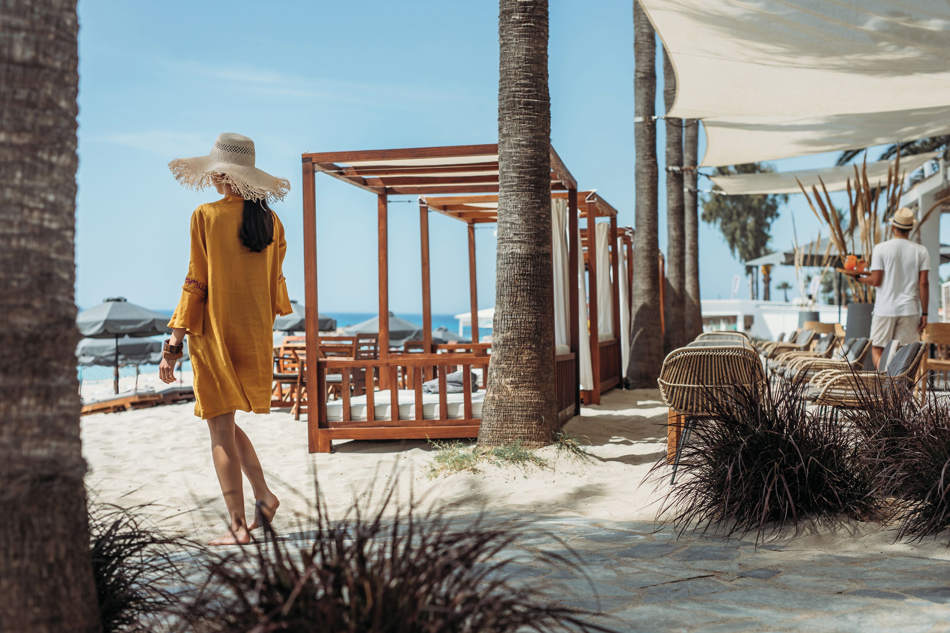 A beach setting with wooden structures, palm trees, and lounge chairs.