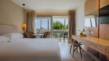 Une chambre d’hôtel avec un lit, une table à manger, des chaises, une télévision et un balcon avec vue.