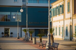 A hotel with a blue facade, outdoor seating, and palm trees.