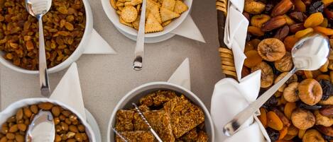 Four bowls of snacks with spoons, arranged on a table.