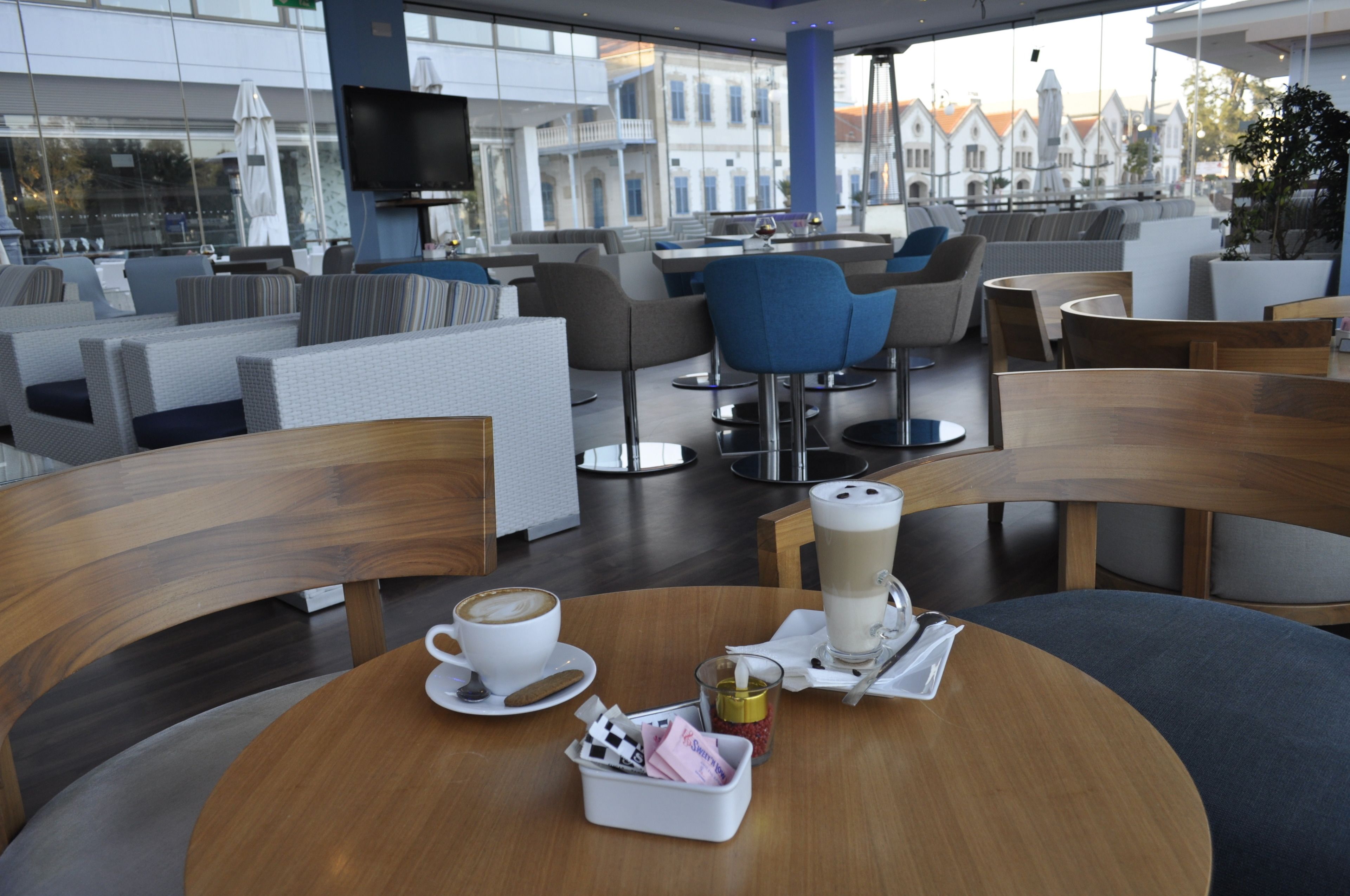 Un café moderne avec des tables rondes, des sièges confortables et une vue sur le paysage urbain.