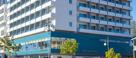 A multi-story hotel with a modern design, featuring a prominent entrance with glass doors and a blue awning.