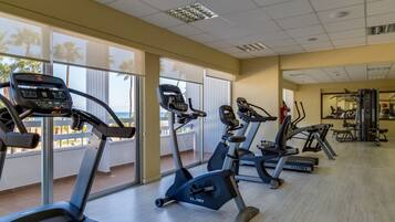 Un gimnasio con cintas de correr, bicicletas estáticas y máquinas de pesas.