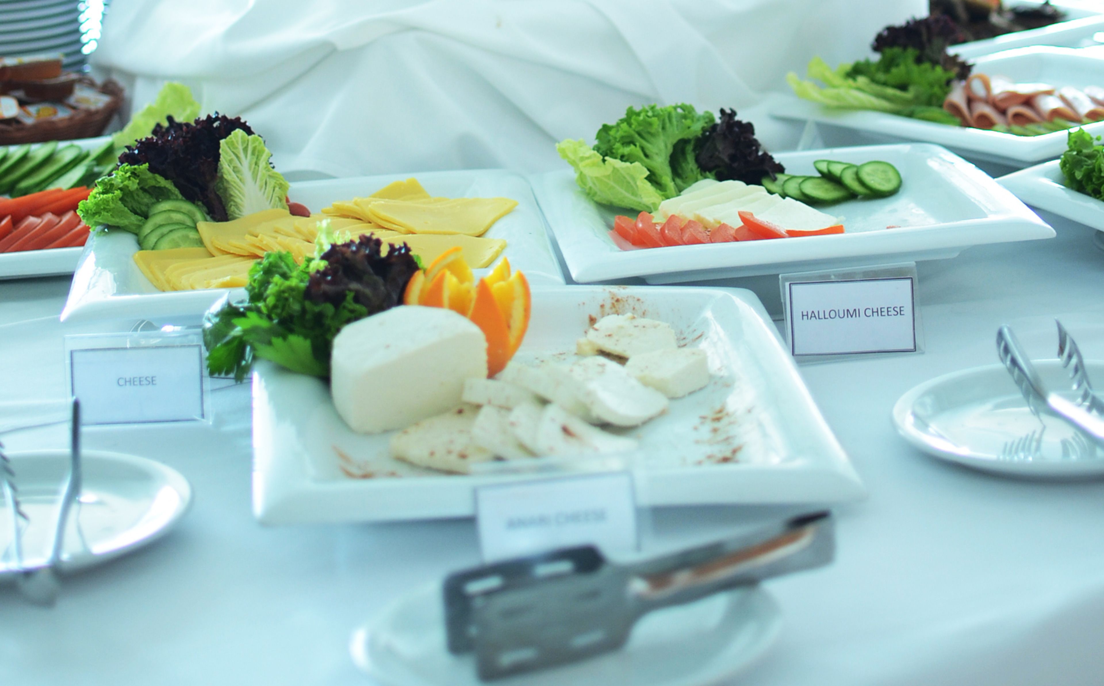 A buffet with various food options including cheese, vegetables, and sliced meats.