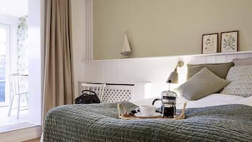 Et hotelværelse med seng, et natbord, en lampe, kaffemaskine og udsigt til det fri.