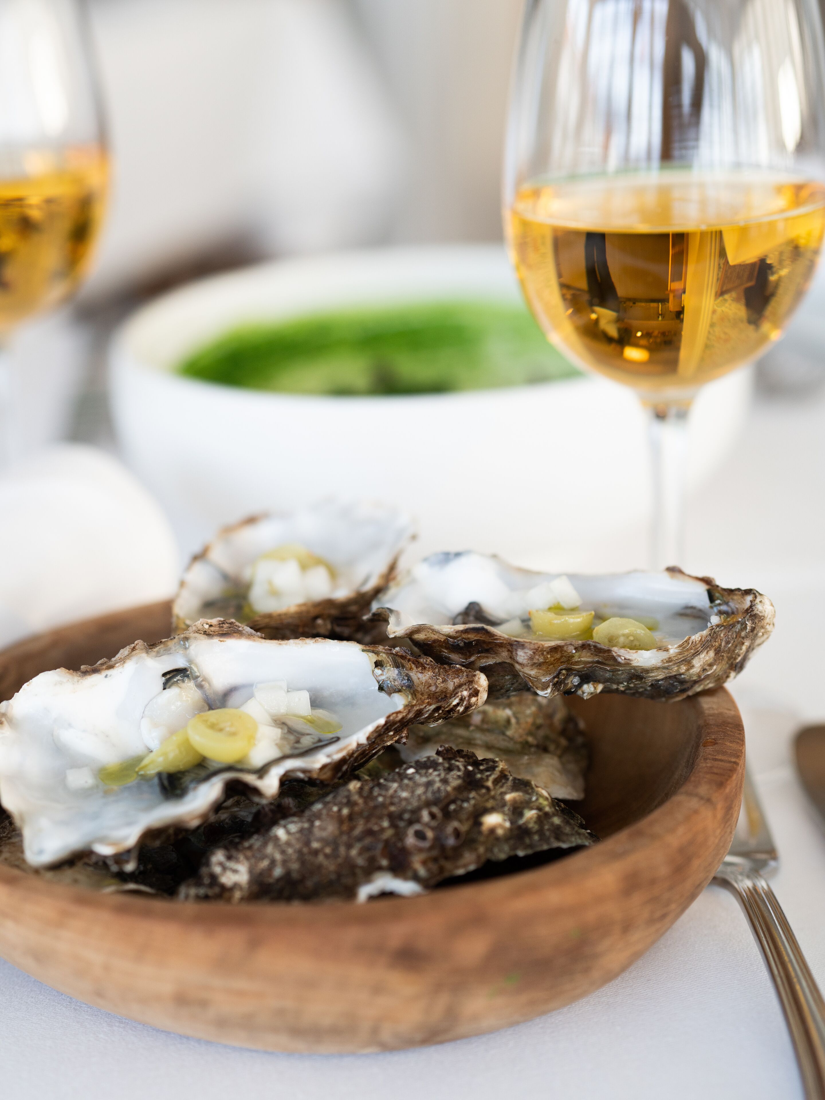 A wooden bowl containing oysters with a fork beside it.