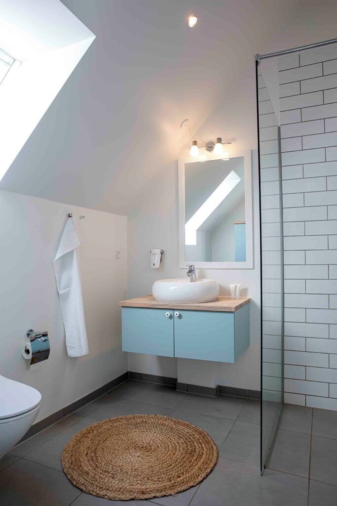 Ein modernes Badezimmer mit Dachfenster, Waschbecken, Spiegel und Dusche.