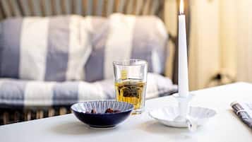 Een tafel met een kaars, een kop thee en een schaal met lekkernijen.