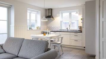 Una cocina moderna con armarios blancos, una mesa de comedor y mobiliario a rayas.