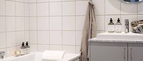Une salle de bain moderne avec une baignoire blanche, un meuble-lavabo avec un miroir et des articles de toilette posés sur le comptoir.