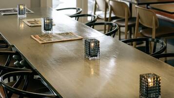 Una larga mesa de comedor con candelabros, lámparas colgantes y sillas.
