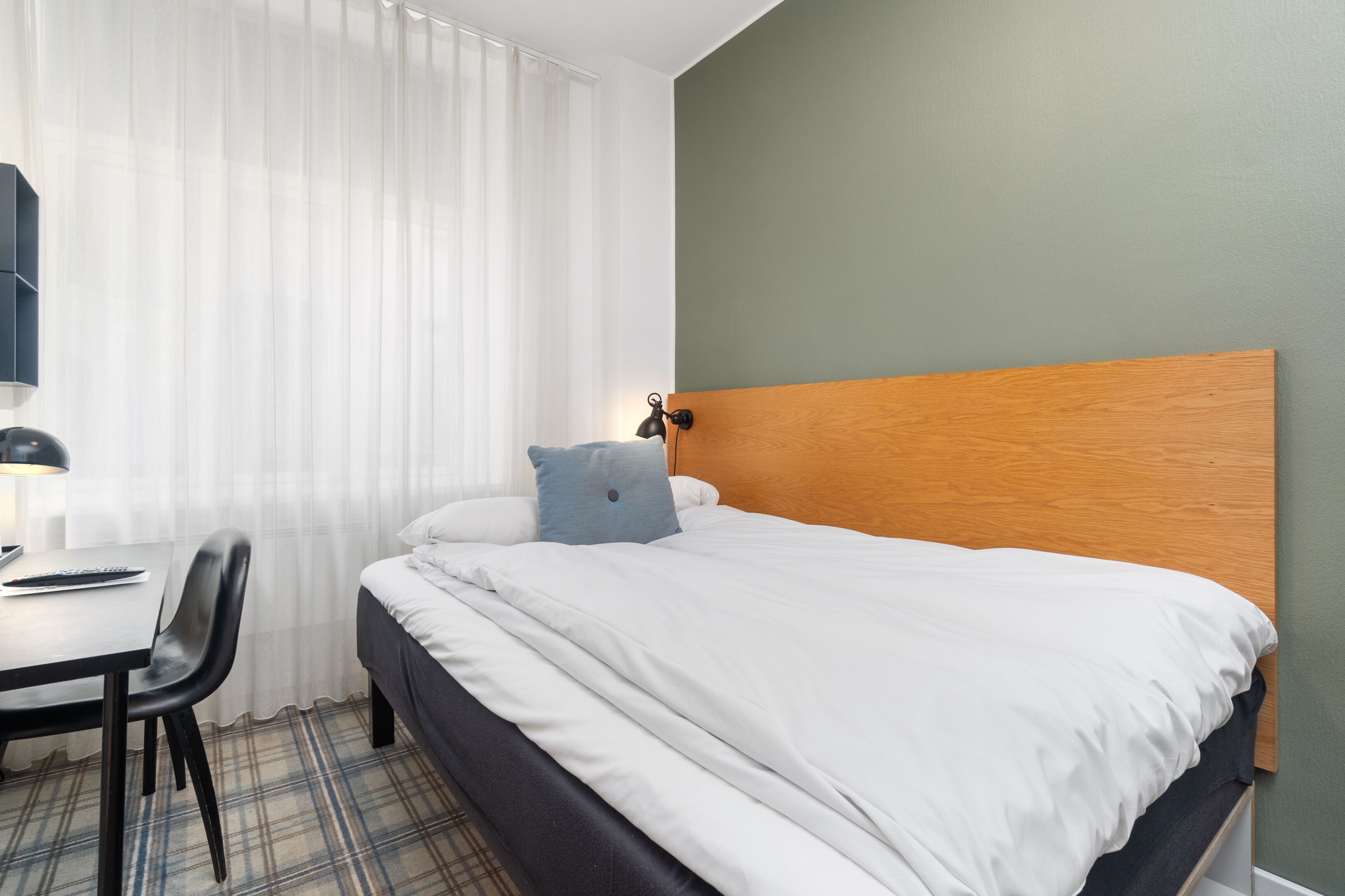A hotel room with a bed, a desk, and a chair.