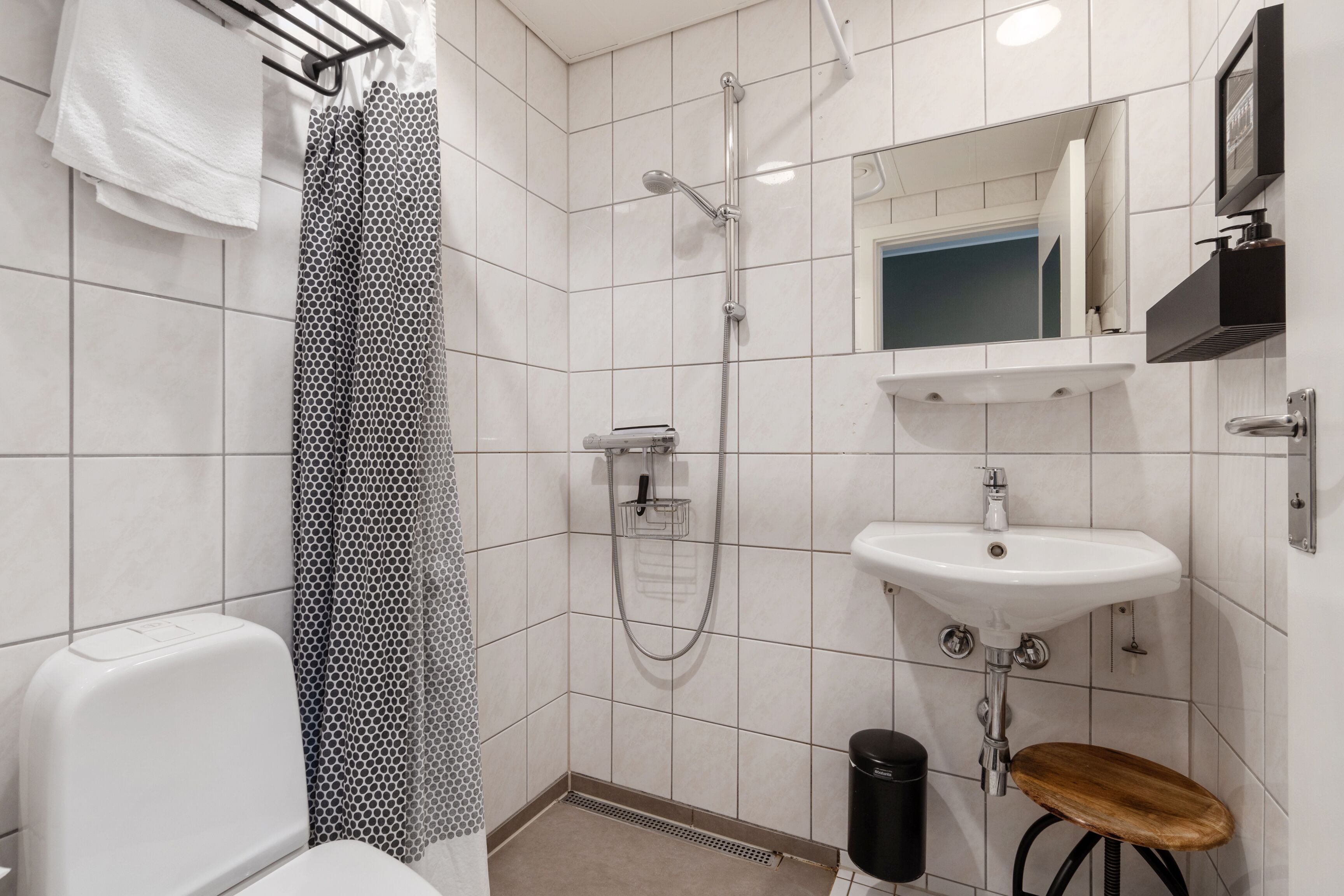 Une salle de bain équipée de toilettes, d’une douche, d’un lavabo et d’un petit tabouret.