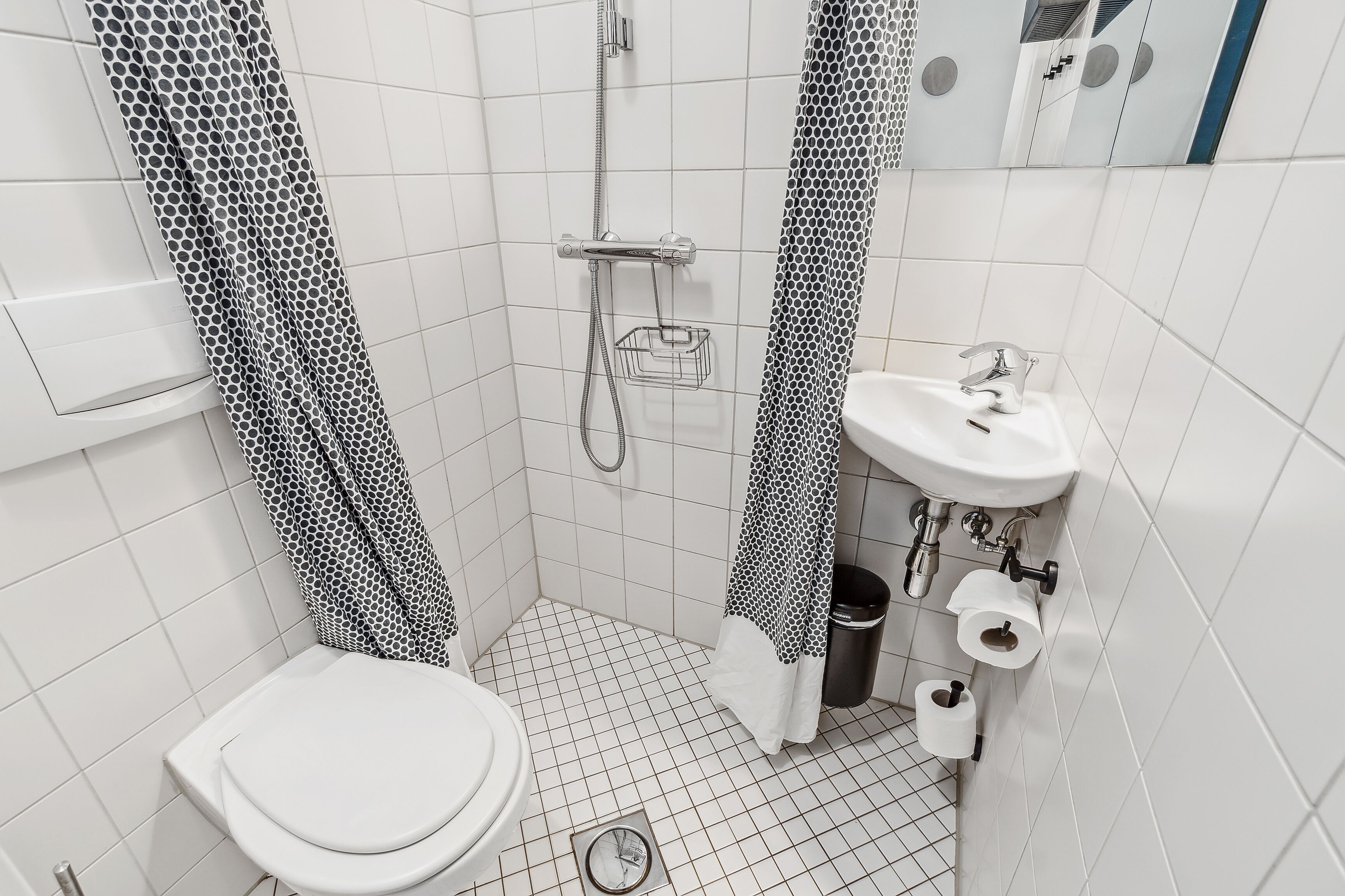 Un baño pequeño y moderno, con inodoro, lavamanos y ducha.