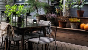 Un área de comedor al aire libre con una mesa, sillas y plantas en macetas.
