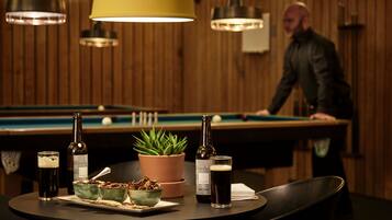 A pool table with a bottle of beer and a glass of beer on a table.