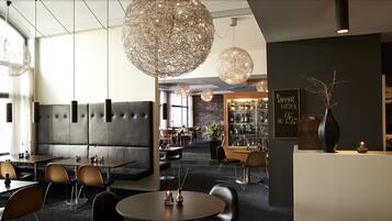 A modern restaurant interior with round tables, cushioned seating, and decorative spherical hanging lights.