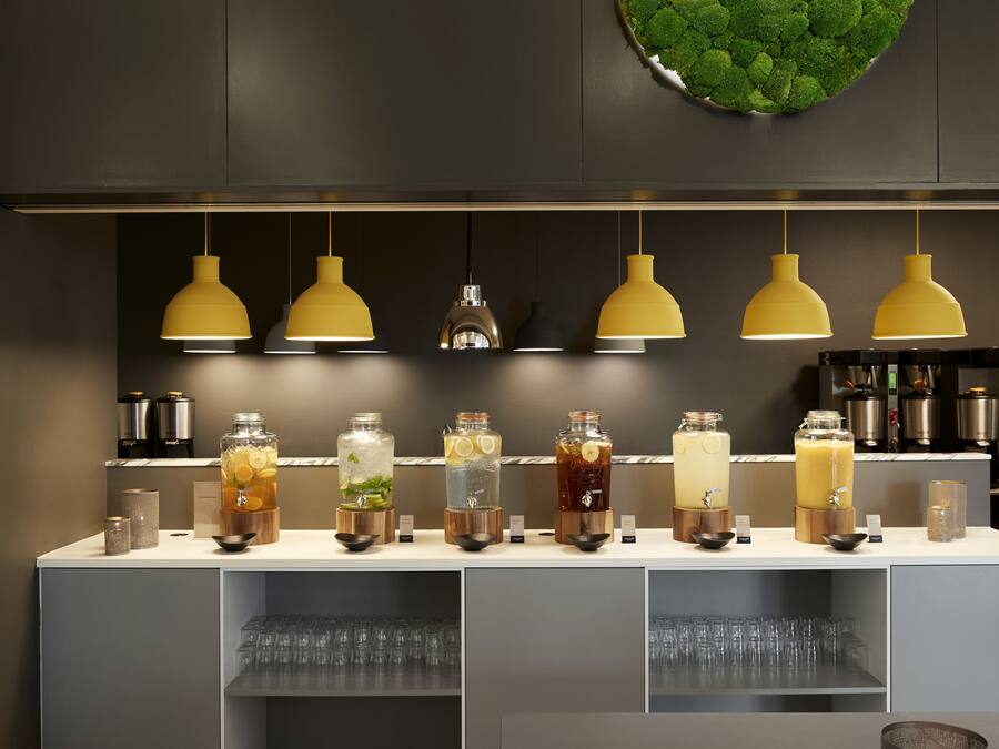 A bar area with multiple beverage dispensers and hanging pendant lights.