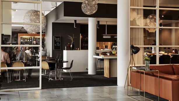 Un intérieur moderne comprenant un coin repas, un bar et un espace détente avec un canapé et une lampe.