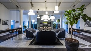 Un hall d’entrée moderne avec un espace salon central, un comptoir d’accueil et une grande plante en pot.