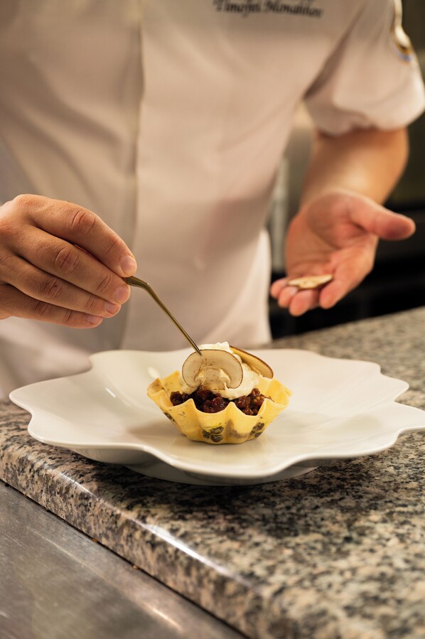 Una persona sosteniendo una cuchara sobre un plato con base amarilla y parte superior blanca, sobre un plato blanco.