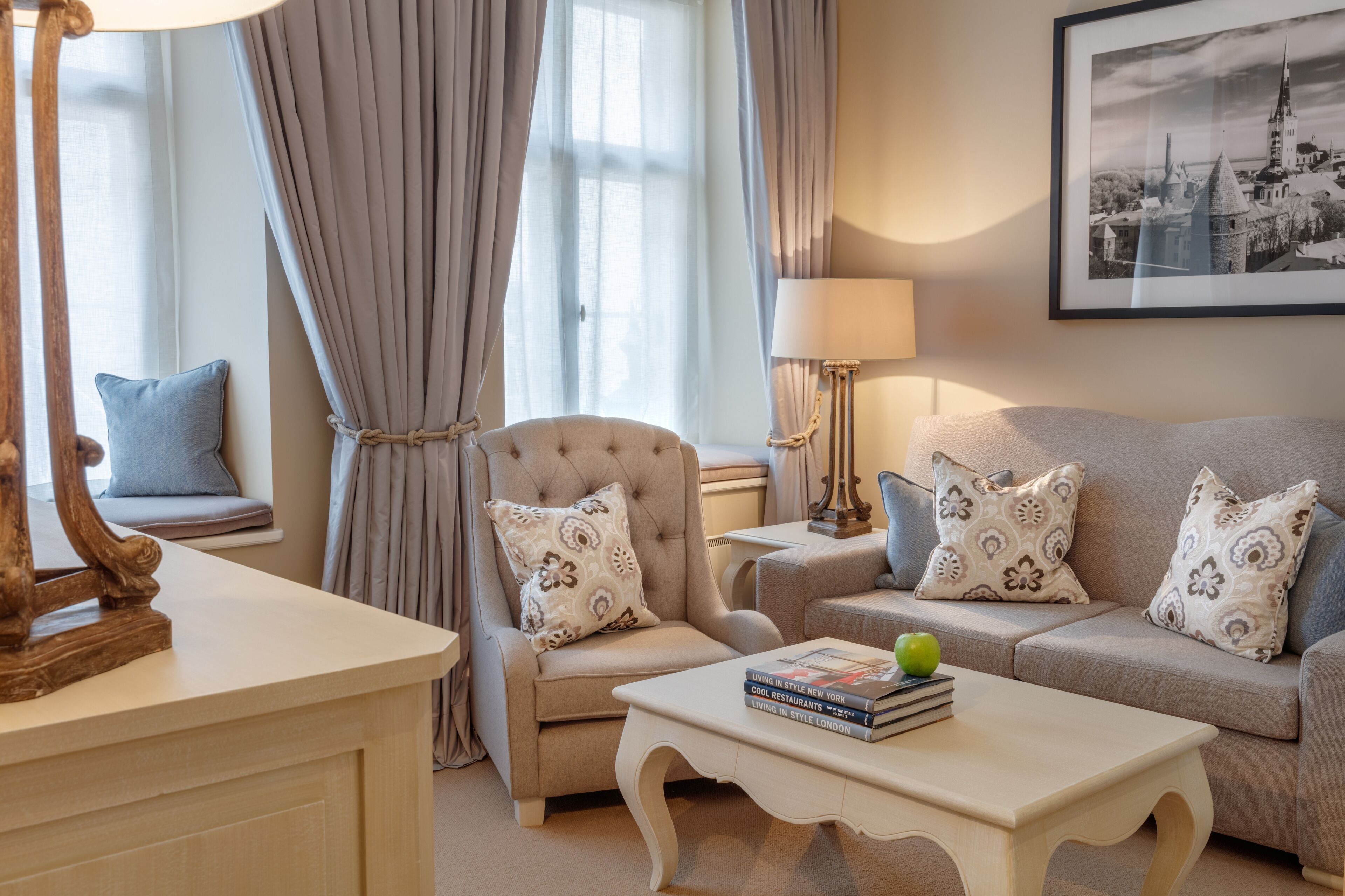 A living room with a sofa, armchair, and a coffee table with books and an apple.