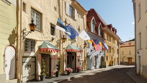 A cobblestone street lined with historic buildings, some with European flags displayed. - Schlössle Hotel - Small Luxury Hotels of the World (Tallinn)