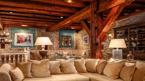 A cozy living room with a beige sectional sofa, wooden beams, stone walls, and a fireplace. - Schlössle Hotel - Small Luxury Hotels of the World (Tallinn)