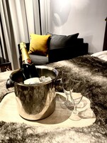 Un minibar con una botella de champán, dos copas y una alfombra mullida.