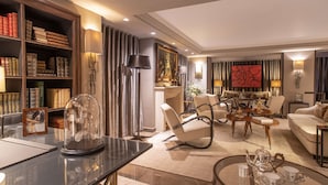 A well-lit living room with a bookshelf, a glass dome display, and a seating area with a sofa and chairs. - Esprit Saint-Germain (Paris)
