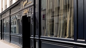 A black facade of a hotel with the name "Emin" and "Hotel" in gold lettering, large windows, and a door with a handle. - Esprit Saint-Germain (Paris)