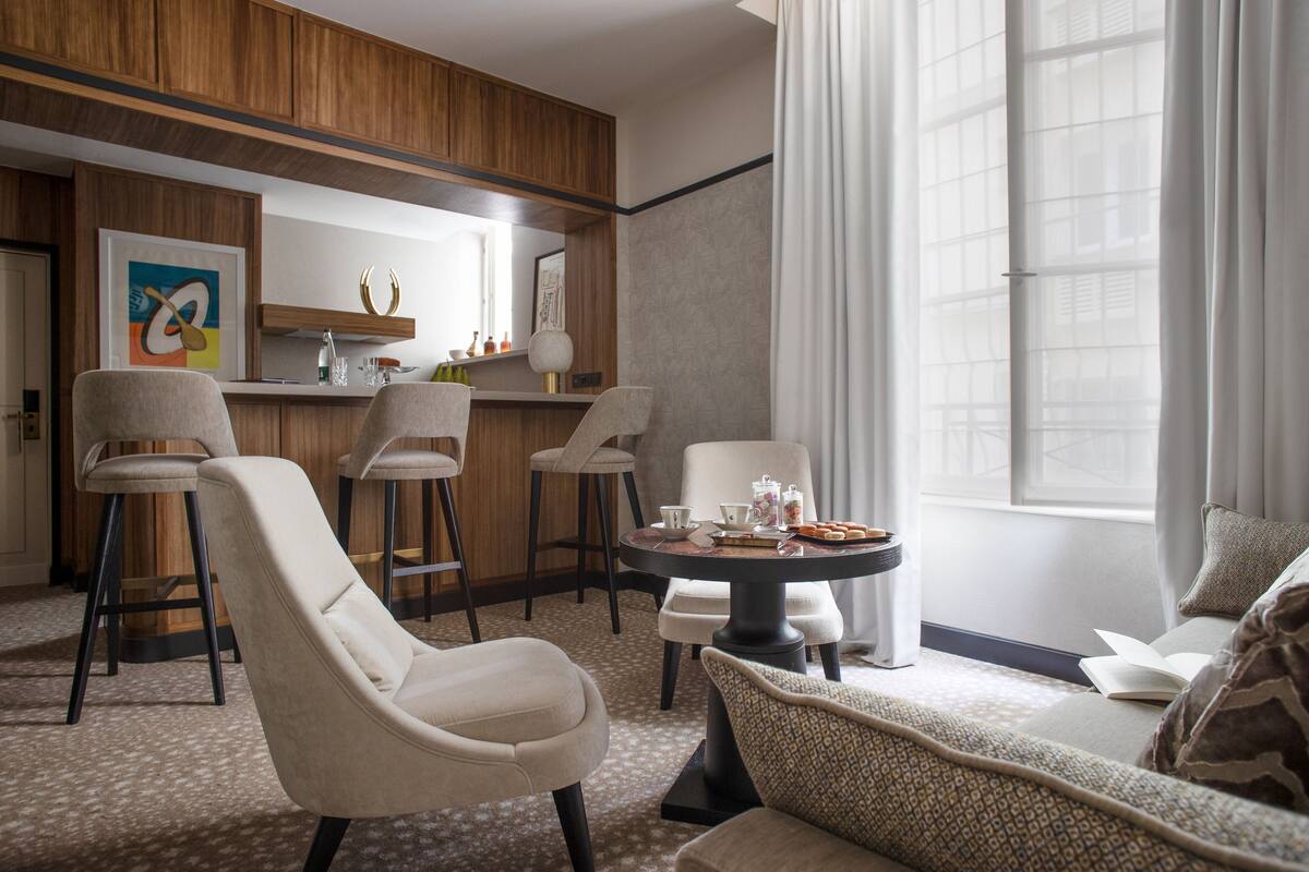 A modern hotel room with a dining area, a sofa, and a bar.