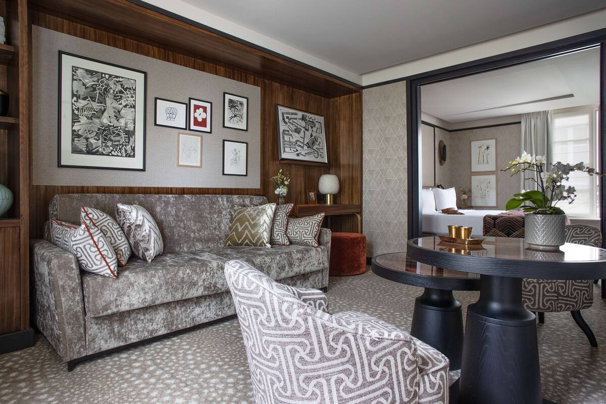 A living room with a sofa, patterned cushions, a round table, and framed artwork on the wall.