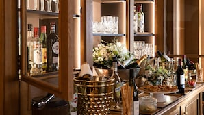 A bar area with shelves of liquor bottles, glasses, and a decorative vase with flowers. - Esprit Saint-Germain (Paris)