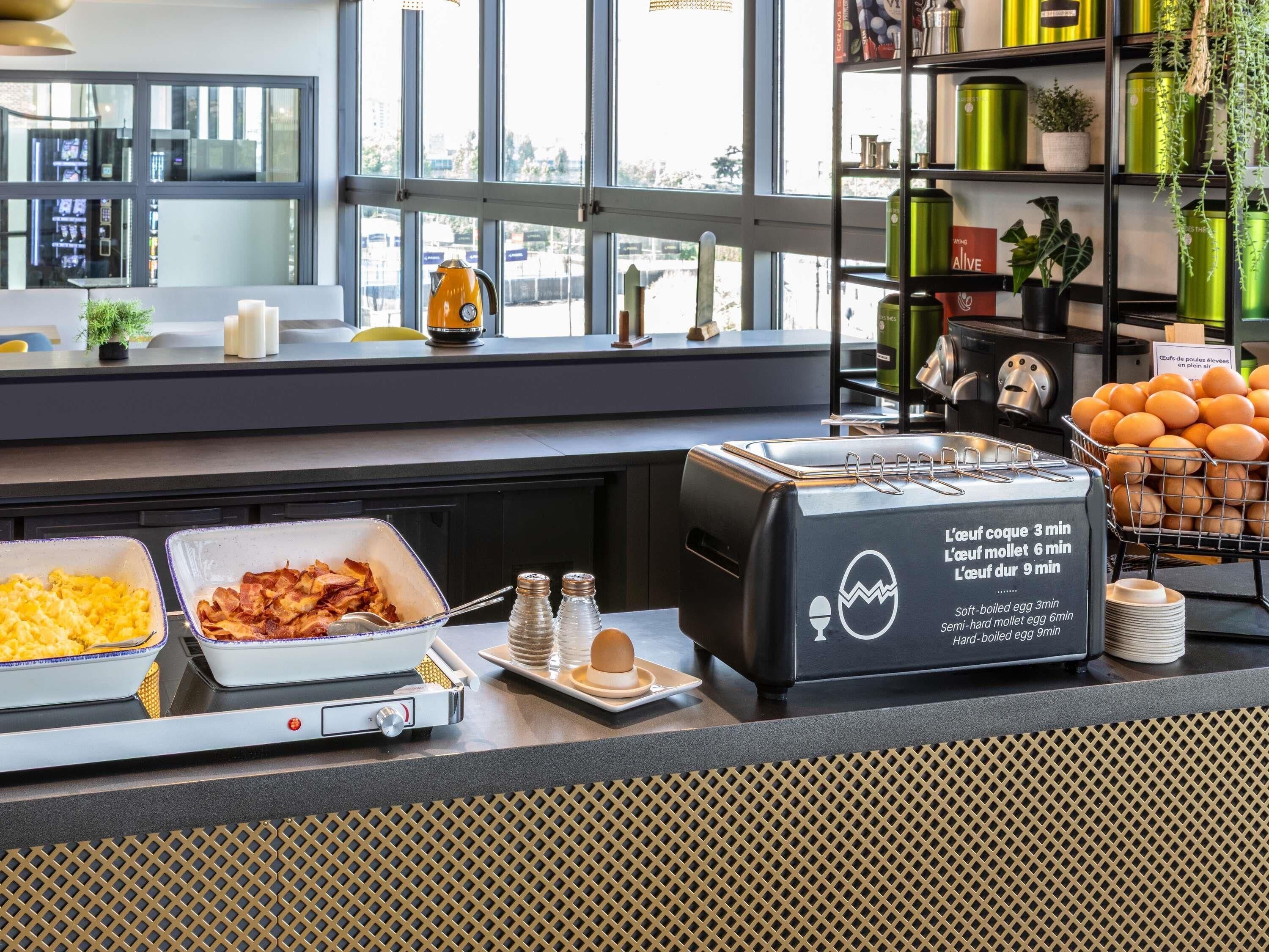 A breakfast buffet with various food options and a toaster displaying cooking times for eggs.