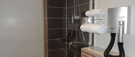 A modern bathroom with a shower, a towel dispenser, and a toilet.