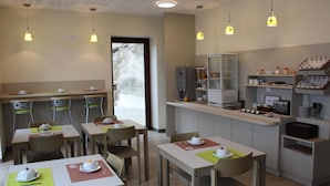 A modern cafe with tables and chairs, a counter with a coffee machine, and a view of the outdoors. - The Originals Hotels City Poitiers Continental (Poitiers)