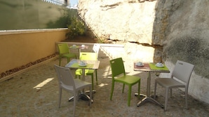 An outdoor patio with tables and chairs, a stone wall, and a fence. - The Originals Hotels City Poitiers Continental (Poitiers)