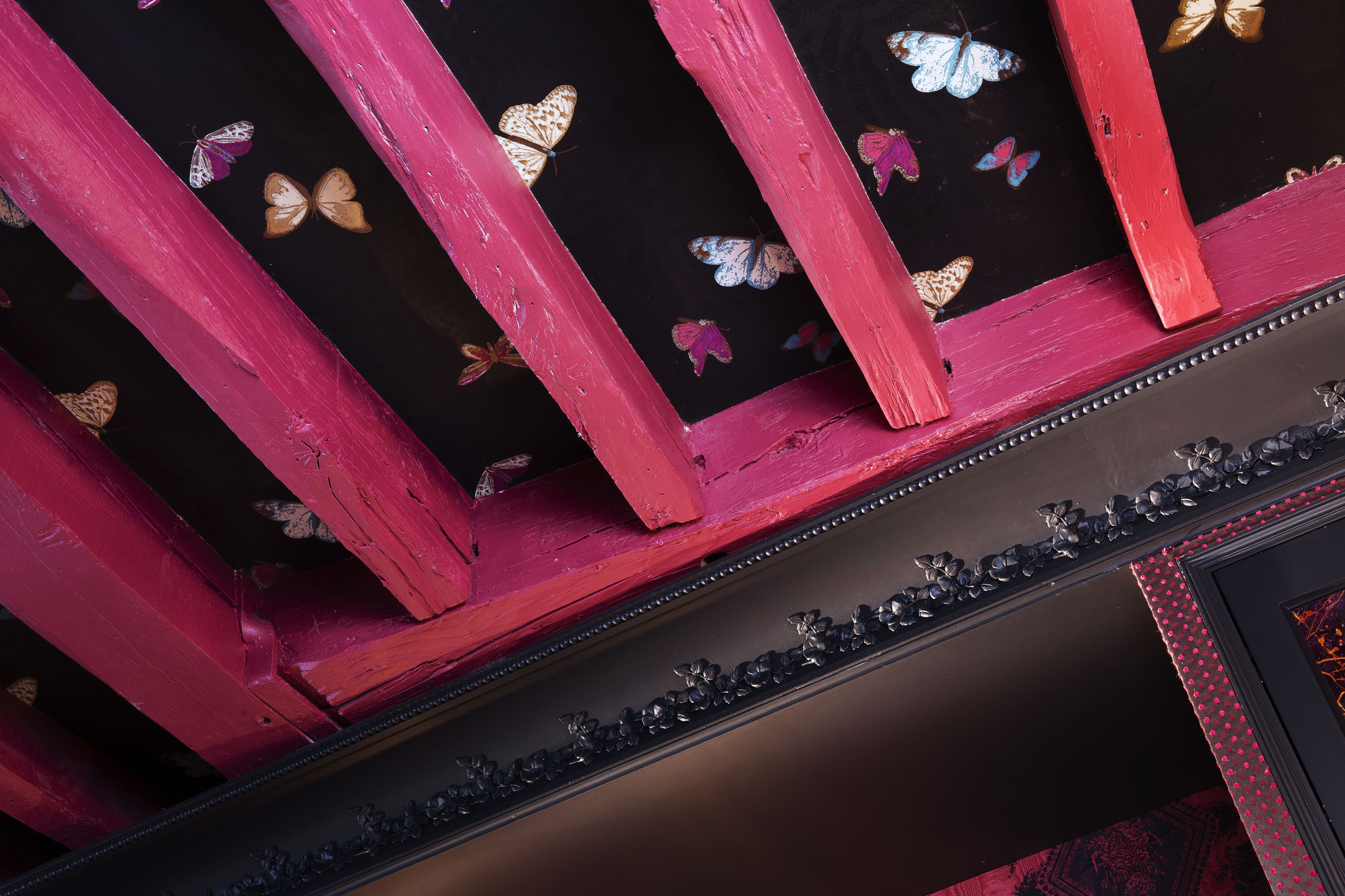 A ceiling with red beams and butterfly decorations.