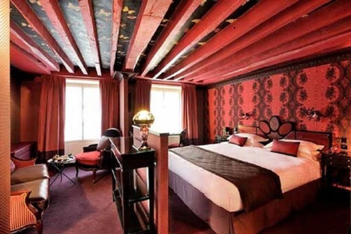 A hotel room with a large bed, a desk, a chair, and a window with curtains.
