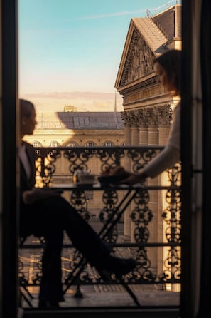 A view from a balcony with ornate metal railings, overlooking a building with classical architecture and a clear sky. - Hotel Les Dames du Panthéon (Paris)