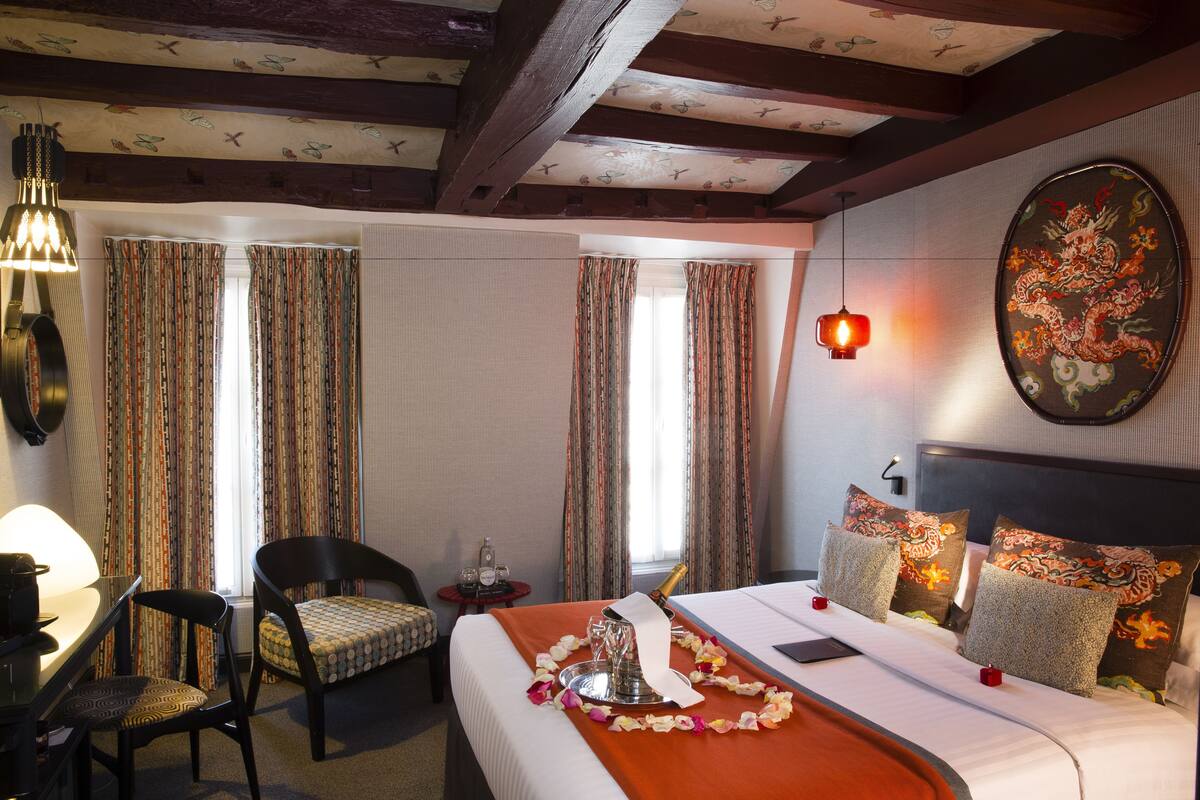 A hotel room with a bed, a desk, a chair, and a window with curtains.
