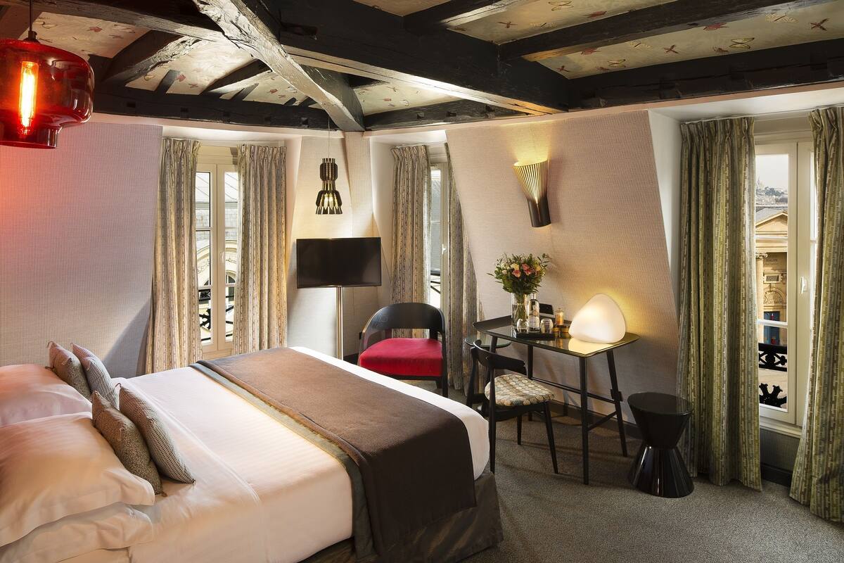 A hotel room with a bed, a desk, a chair, and a TV.