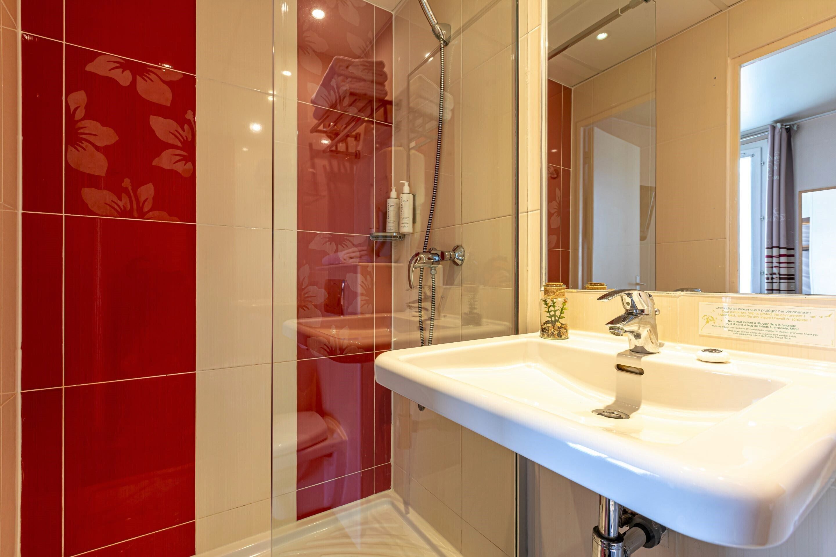 Une salle de bain moderne avec une douche à parois de verre, un lavabo blanc et un miroir.